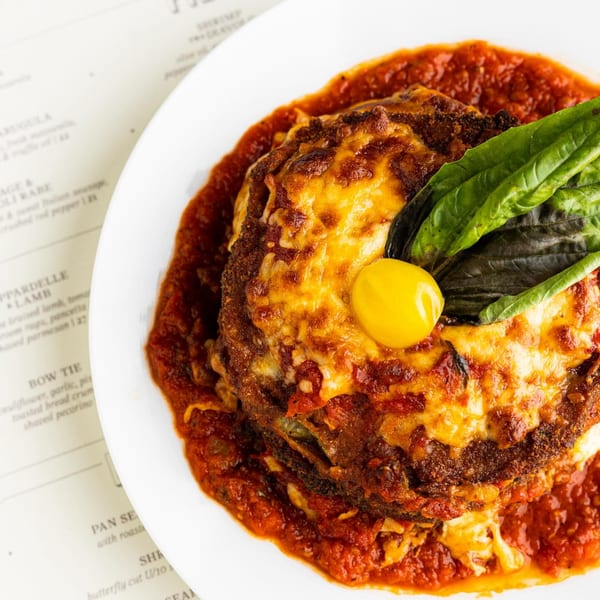Nunzi's Italian dish with melted cheese, tomato sauce, basil, and a yellow cherry tomato.