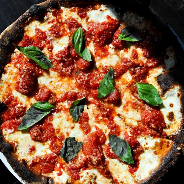 Nunzi's Italian pizza with rich red sauce, melted mozzarella, and fresh basil leaves.